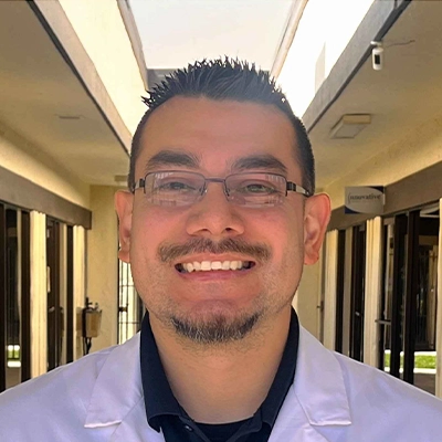 Chiropractor Alex Sanchez Smiling In Lab Coat