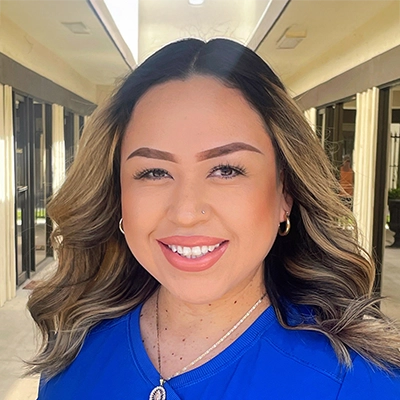 Office Manager Palmira Cabello-Campos Smiling In Scrubs