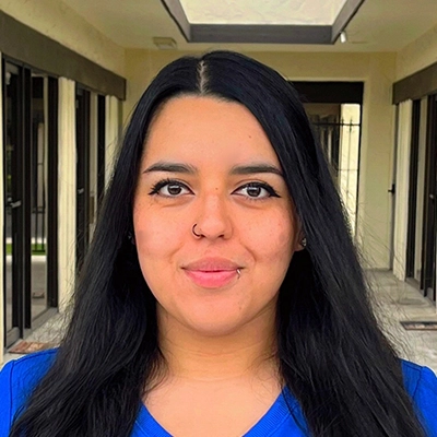 Front Desk Manager Rebecca Alvarez Smiling In Scrubs